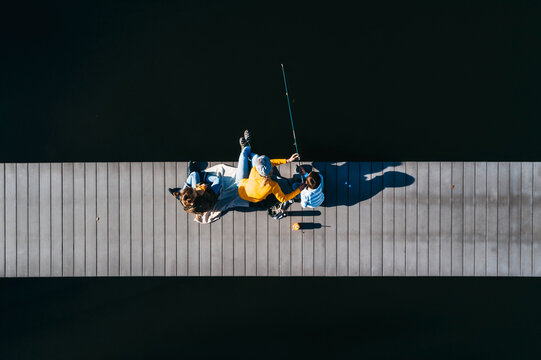 Family sitting on jetty, fishing in autunm