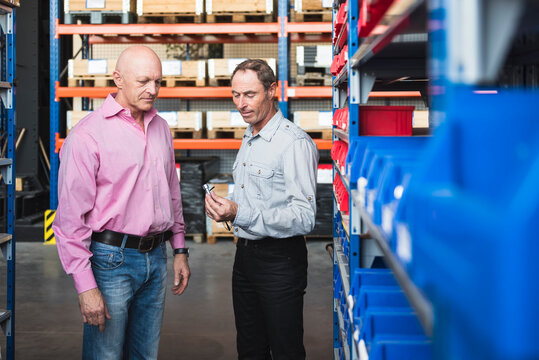 Two men in storehouse examining screw
