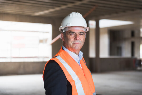 Portrait of man wearing safety vest in building under construction