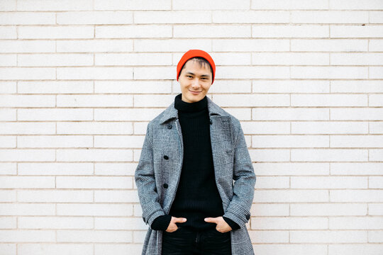 Portrait of stylish young man wearing cap, black turtleneck pullover and grey coat