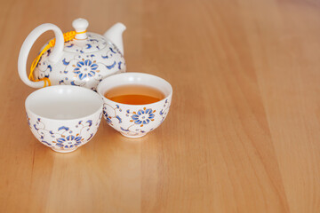 Traditional Asian tea set with ceramic teapot and cups filled with hot tea on wooden table and copy space. Elegant tea ceremony and relaxation concept for wellness, hospitality, and lifestyle themes