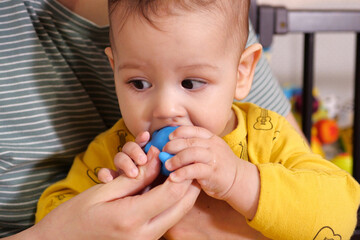 Cute adorable newborn baby playing with colorful rattle toy. baby with teether. six months old lovely baby portrait on white with teether toy