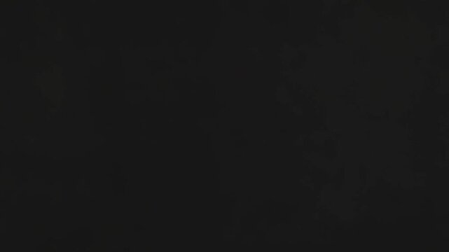 Natural light pouring through an unseen window forms contrasting parallel lines of bright light and dark shadows across the grey wall and floor, creating a minimalist geometric pattern