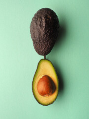 Two organic ripe avocados on a green studio background