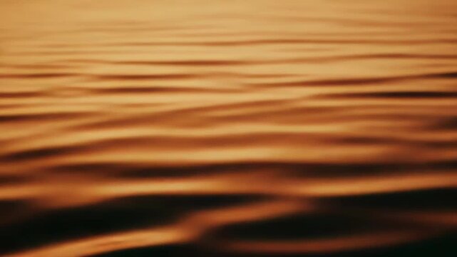 Water surface creating an abstract pattern with small waves and ripples, reflecting the warm orange glow of a sunset, offering a peaceful and tranquil scene