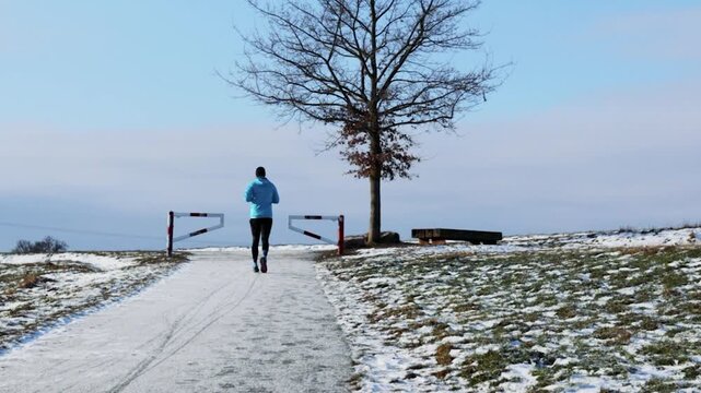 Runner Jogging Snowy Winter Path Bare Tree Video, Winter Sport Outdoor Fitness, Blue Jacket, Cold Weather Running, Nature Trail Cinematic Footage