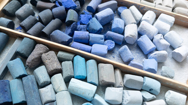 Blue shadow soft pastel chalk collection in artist wooden box. Colored stick pieces for pastel painting top view.