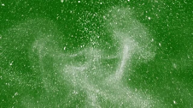 Cinematic slow motion explosion of shimmering white dust particles and glitter splashing across a professional green chroma key screen background for visual effects compositing video