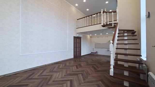 Spacious two-level interior with herringbone parquet floor, white walls, wooden staircase with white balusters, recessed ceiling lights, minimalist design &mdash; bright and airy.
