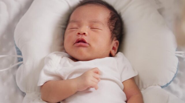 Newborn baby resting in soft baby nest. Symbol of early sleep habits, growth, and development.