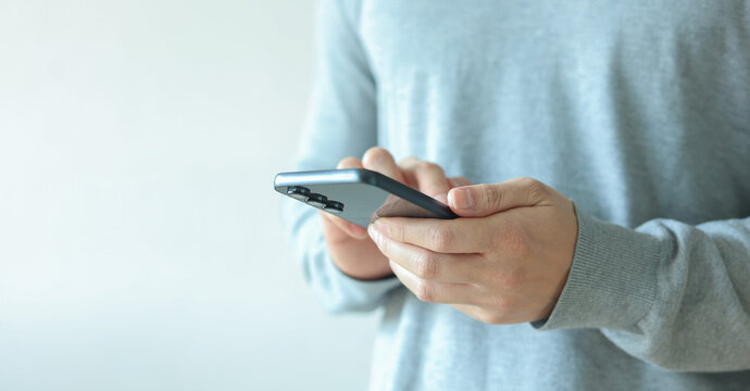 close up businessman hand hold smartphone to surfing the internet and check work or mail on website while sit in the living room in weekend for business technology and lifestyle concept