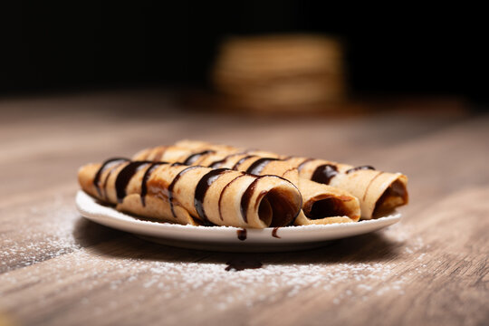 Crepes rellenos con salsa de chocolate sobre plato blanco