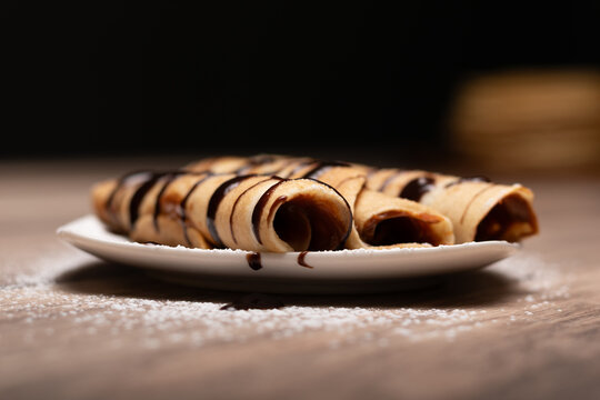 Crepes rellenos con salsa de chocolate sobre plato blanco