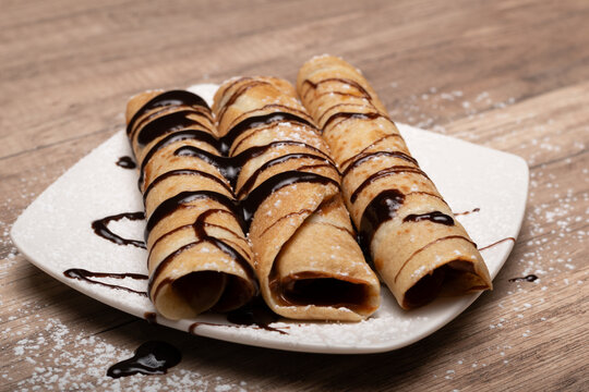 Crepes rellenos con salsa de chocolate sobre plato blanco