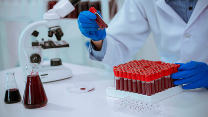 Science. A doctor's hands are picking up a blood sample tube from a shelf for laboratory analysis;...