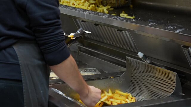Cooking french fries in professional deep fryer at street food kitchen