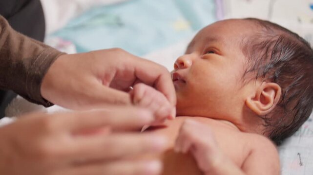 Adult hand gently holds newborn fingers. Symbolizes caring, protection, and unconditional parental love.