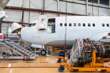 Passenger plane near to high-bypass turbofan airplane engine in aircraft hangar