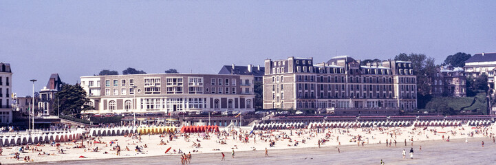 Dinard, Ille-et-Vilaine, France, August 1973: crowded summer beach with bathers and striped cabins...
