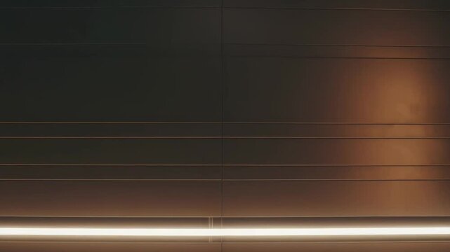 Modern wall featuring parallel architectural lines and a bright horizontal light strip illuminating the dark surface, creating an abstract and minimalist background with warm ambient light