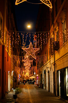 European street decorated with glowing star lights and garlands at night. Warm festive atmosphere representing Christmas season, winter travel and city celebration.