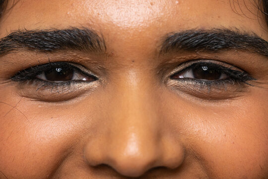 Extreme close-up eye area is showing black eyeliner, lashes, pores under warm studio lighting