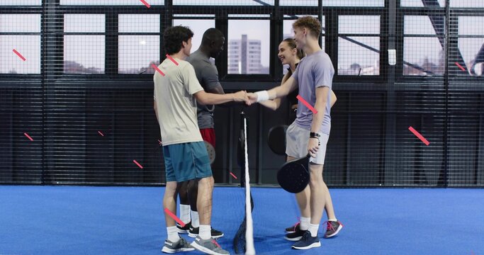 Shaking hands adult players meeting at net on blue court, holding black paddles in athletic clothes