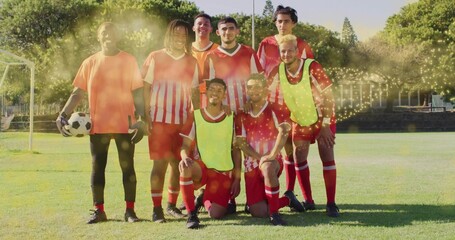 Fototapeta premium Posing eight soccer players wearing red kits with yellow vests on grassy field, keeper holding ball