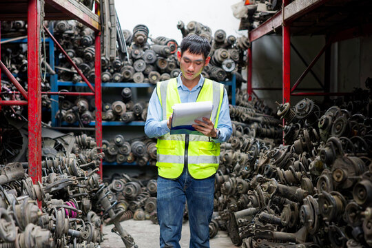 Worker examining auto parts in a warehouse, with stacks of components filling the shelves