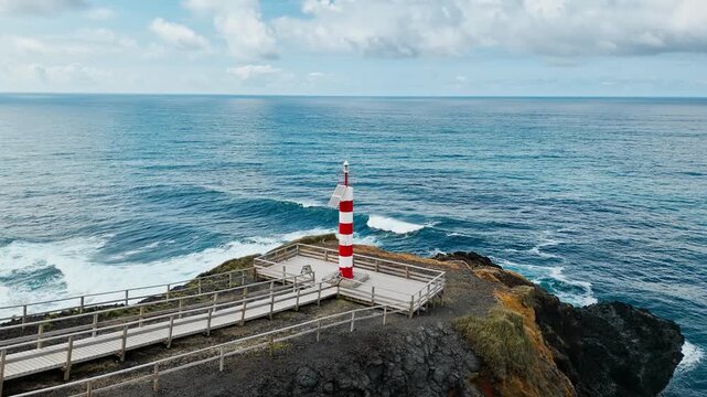Lighthouse Farolim dos Fenais da Ajuda on rugged Atlantic coastline with steep cliffs, Sao Miguel Island. Azores Drone view