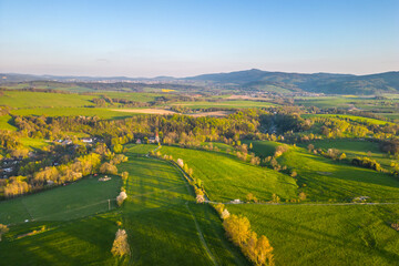 Obraz premium A summer landscape with fields and trees. The land is green with hills in the background. The scene captures nature in its seasonal form.