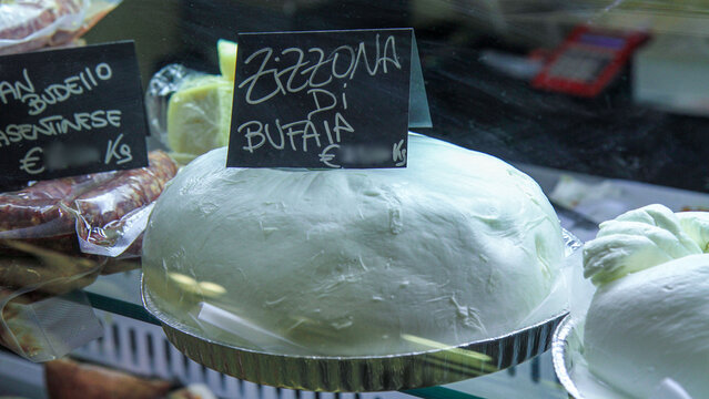 Fresh Italian buffalo mozzarella (mozzarella di bufala) in a market refrigerator with price tag. Gourmet dairy product, delicatessen, Mediterranean cuisine concept.