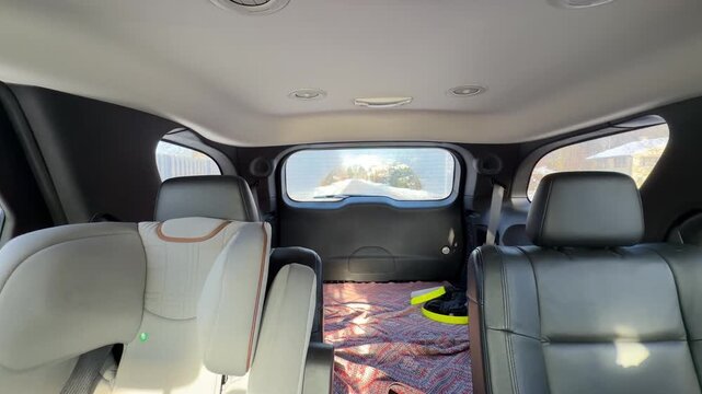 Car Interior with Child Seat and Rear Window View. Interior shot of spacious vehicle showing child safety seat and blanket in trunk area. Rear window frames view of snowy road behind moving car.