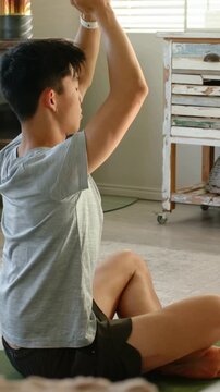 Vertical video: Lowering from arms up, teen moving palms to chest, calming on mat at home with band