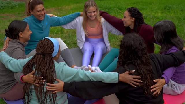 Women circle hugging each other outdoor and doing group meditation - Multi generational female community, unity and diversity concept