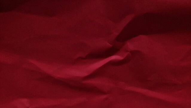 Crumpled dark red paper background with wavy texture. Abstract recycled kraft paper surface. Wrinkled paper backdrop with blank copy space for design.