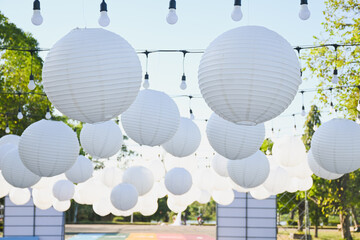 White paper lanterns hanging outdoors under a clear sky.