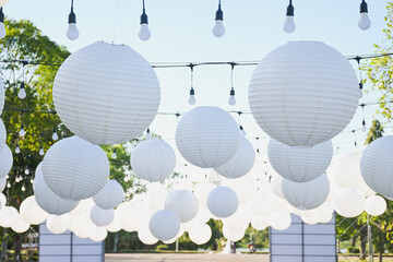 White paper lanterns hanging outdoors under a clear sky.