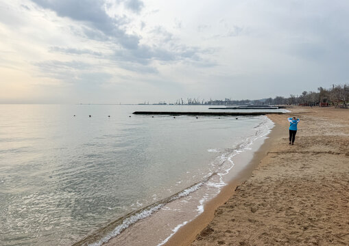 Sandy beach  along the Sea of Azov with industrial port in the distance, Donetsk Oblast, Mariupol, Ukraine