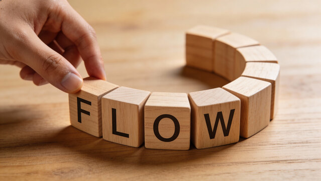 Hand placing 'Flow' wooden blocks for concept of business process