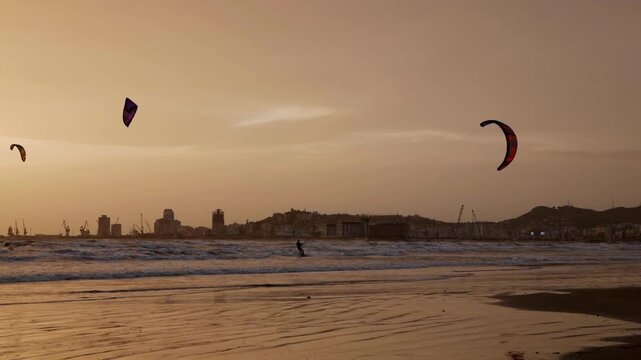 Kiteboarders catching air at sunset on the coast.