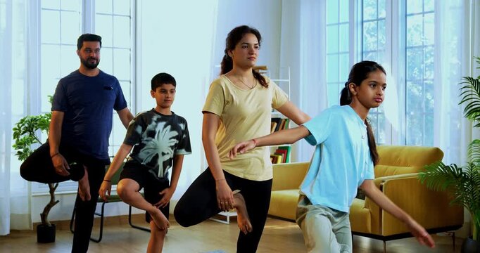 Indian family doing parvatasana yoga at home practicing mountain pose together indoors for healthy body and calm mind during morning routine inside a modern lavish living space