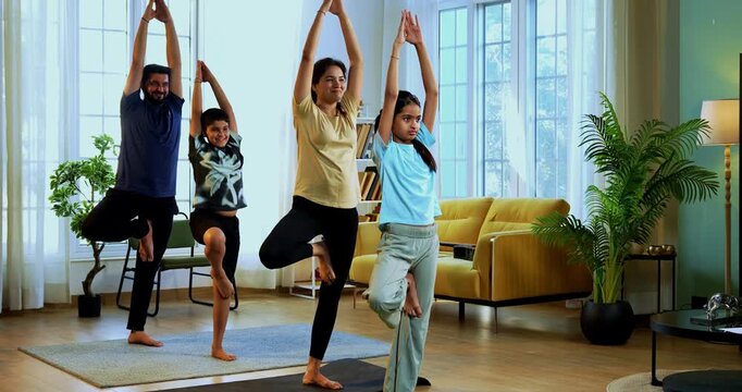 Indian family doing parvatasana yoga at home practicing mountain pose together indoors for healthy body and calm mind during morning routine inside a modern lavish living space