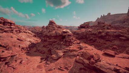Sunlight casts a warm glow on the red rocks of a stunning desert landscape. Unique rock formations rise dramatically against a clear blue sky, evoking feelings of adventure and tranquility.
