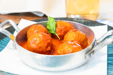 Traditional meatballs served with a basil leaf and tomato sauce.