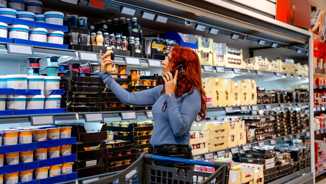 Woman shopping in supermarket aisle with phone