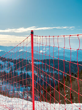 Scenic view of snowy mountain ski trails and safety net