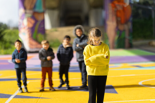 Girl standing alone with arms crossed feeling excluded