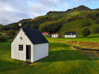 Obraz premium Small Icelandic village, Skógar church or Skógakirkja. Skógasafn - open air complex exploring early Icelandic history, heritage relics and wooden turf-houses. Safnavegur, Skógar, Iceland.