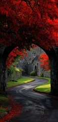 A winding road leads through a stone archway framed by vibrant red foliage. A building is in the distance